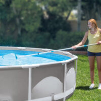 Donna pulisce piscina fuori terra in giardino